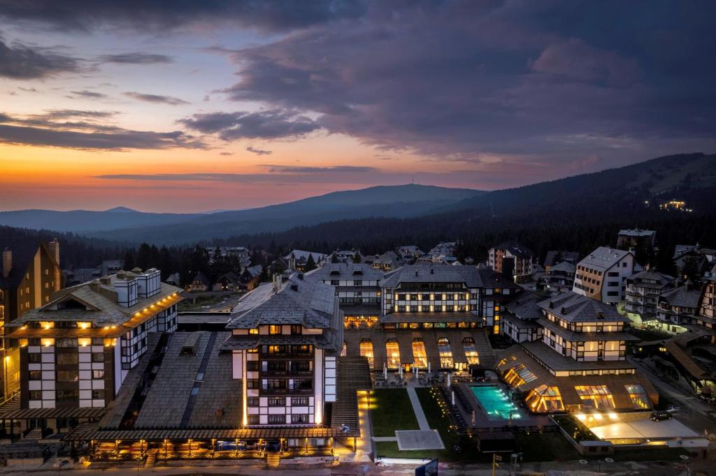 科帕奥尼克Hotel Grand Kopaonik的一座夜晚与山 ⁇ 相映的城市