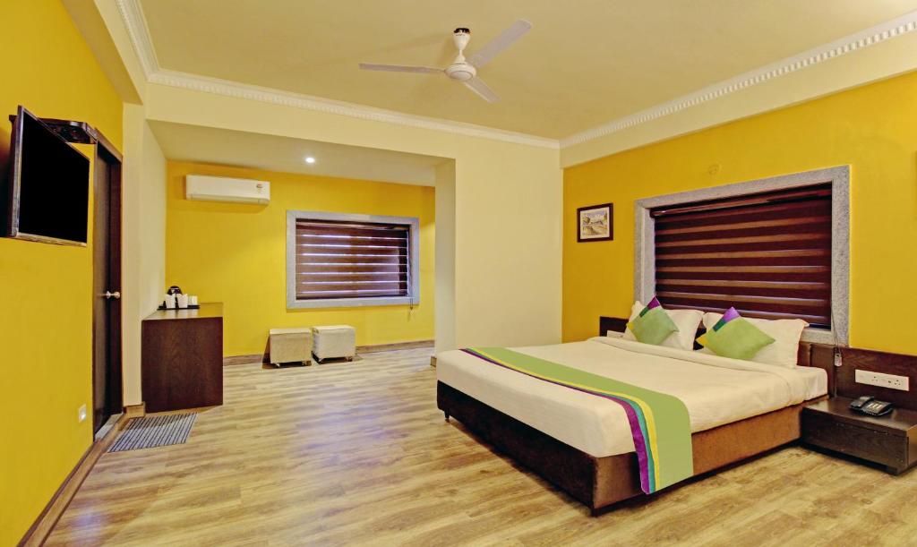 加尔各答Treebo Trend ASL Prime的一间卧室设有一张黄色墙壁的大床