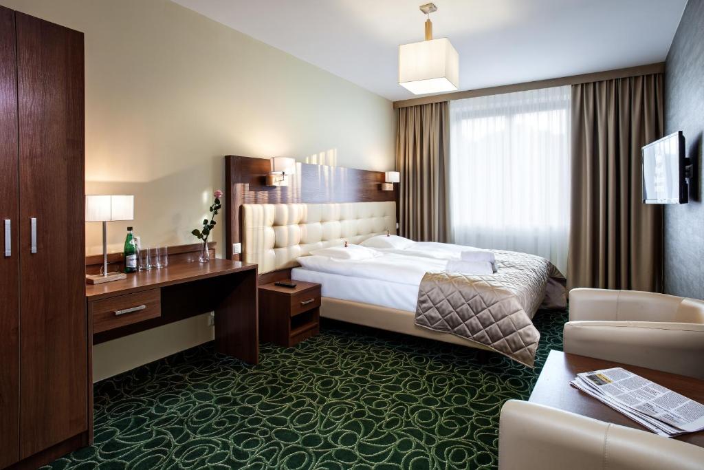 卢布林皇家植物园酒店的配有一张床和一张书桌的酒店客房