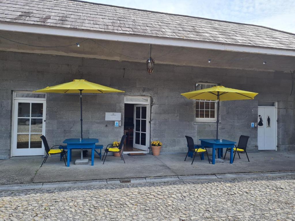 OldcastleLoughcrew Courtyard House的两把桌子和椅子,在大楼前摆放着黄伞