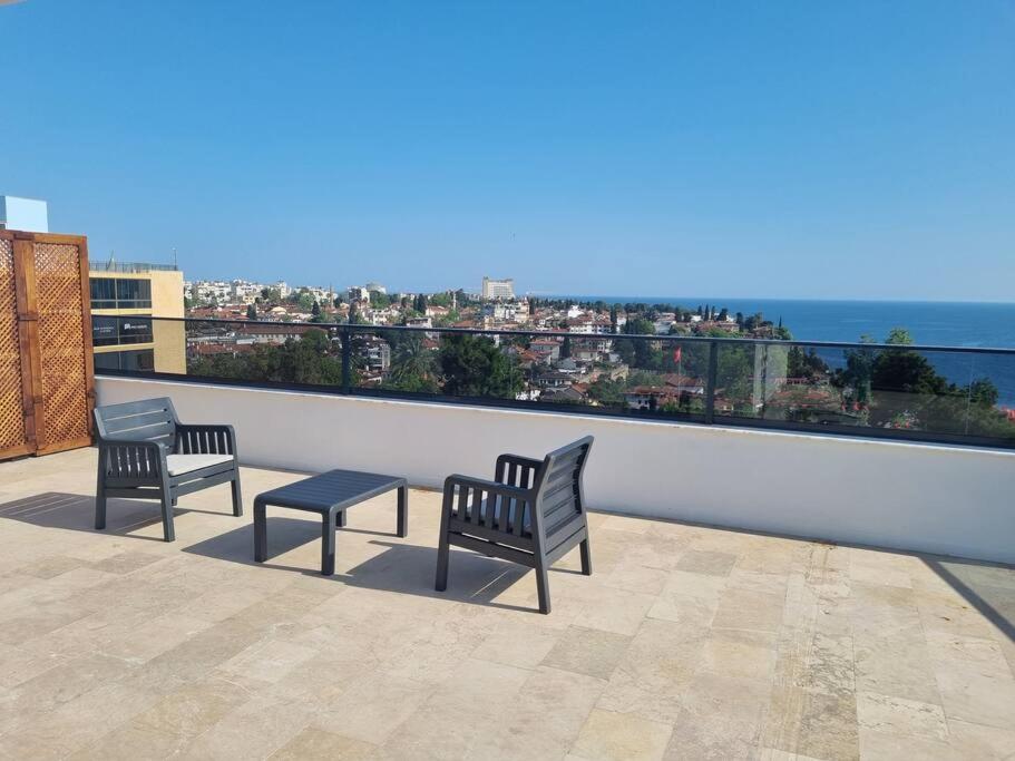 安塔利亚Royal Homes 503的阳台设有2张长椅和1张桌子,俯瞰着大海