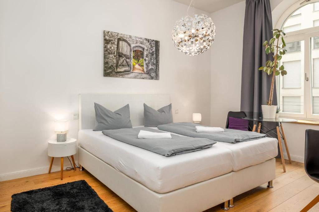 莱比锡Apartments an der Arena Leipzig的卧室配有一张白色大床和吊灯。