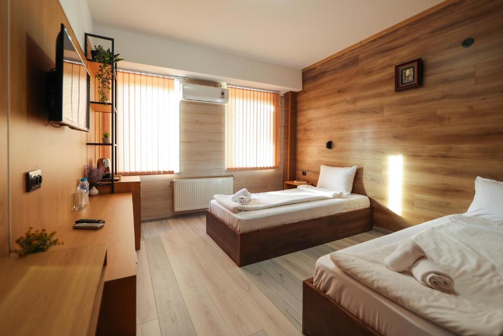 戈采代尔切夫Family Hotel Gotse Delchev的一间带两张床铺的卧室,位于带木墙的房间内