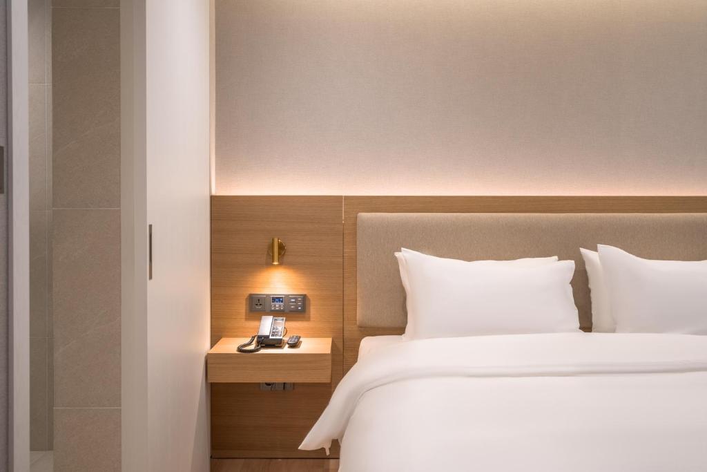 首尔Comfort inn Yeouido的酒店客房设有一张床和一个带时钟的床头柜