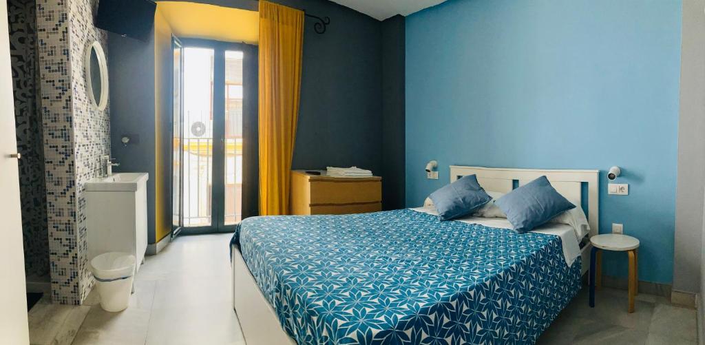 圣玛丽亚港Hostal Baobab的一间拥有蓝色墙壁的卧室和一张带蓝色床单的床