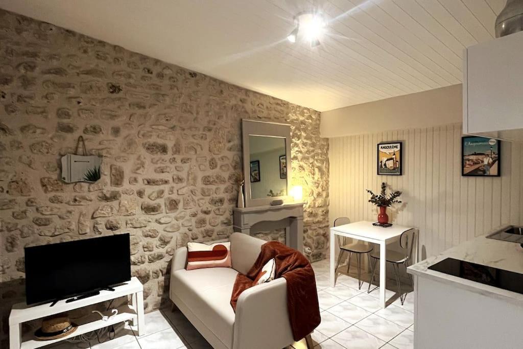 尚尼耶Gîte aux portes d'Angoulême的客厅设有石墙、沙发和电视