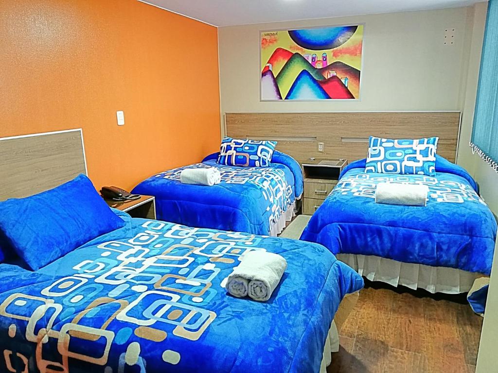 拉巴斯Hostal NAVAL的一间卧室配有三张床和蓝色棉被