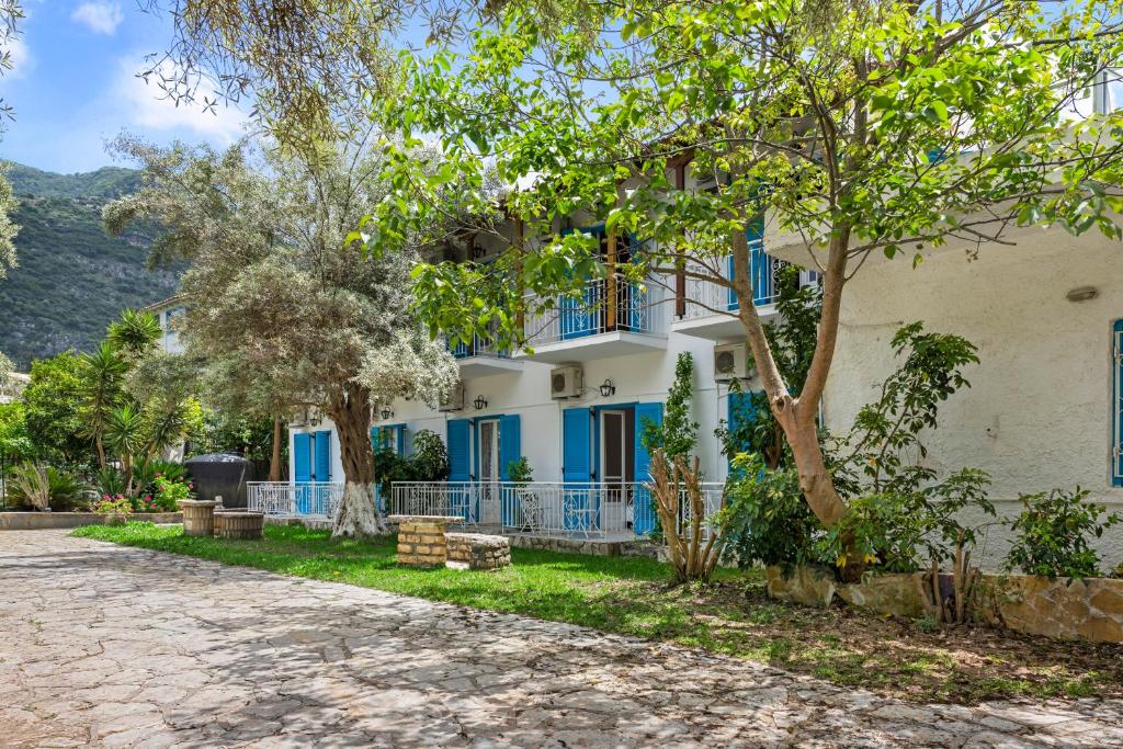 米克罗斯雅洛斯Oceanis Rooms的前面有蓝色百叶窗和树木的房子