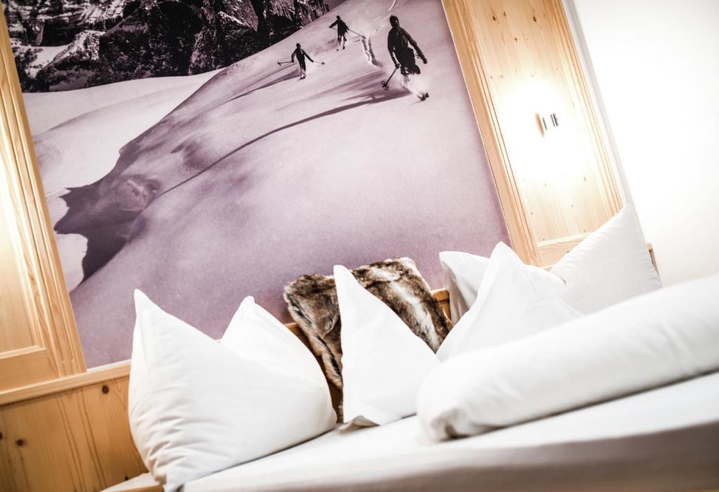塞尔瓦迪加尔代纳山谷Garni Sunela B&B的一张带枕头的床和一张滑雪者的照片