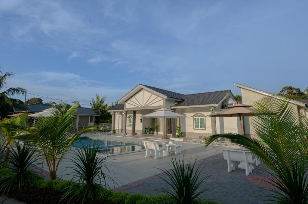 马六甲Villa Dracaena Melaka With Swimming Pool, Hill View and 20 minutes to Town的一座房子,设有一座带椅子和遮阳伞的游泳池