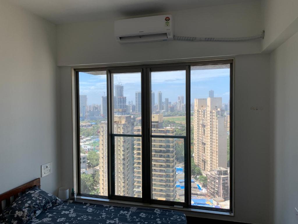 孟买Room in Flat with Amazing City and Sea View的卧室设有大窗户,享有城市美景