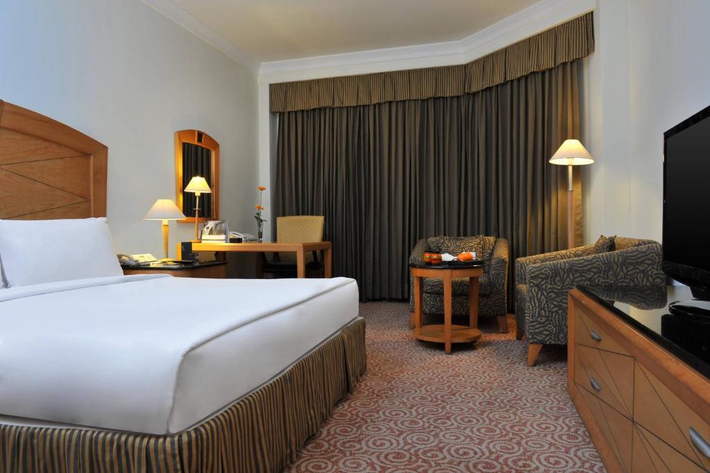 钦奈世茂皇家艾美钦奈酒店的酒店客房配有一张床、一把椅子和一台电视。