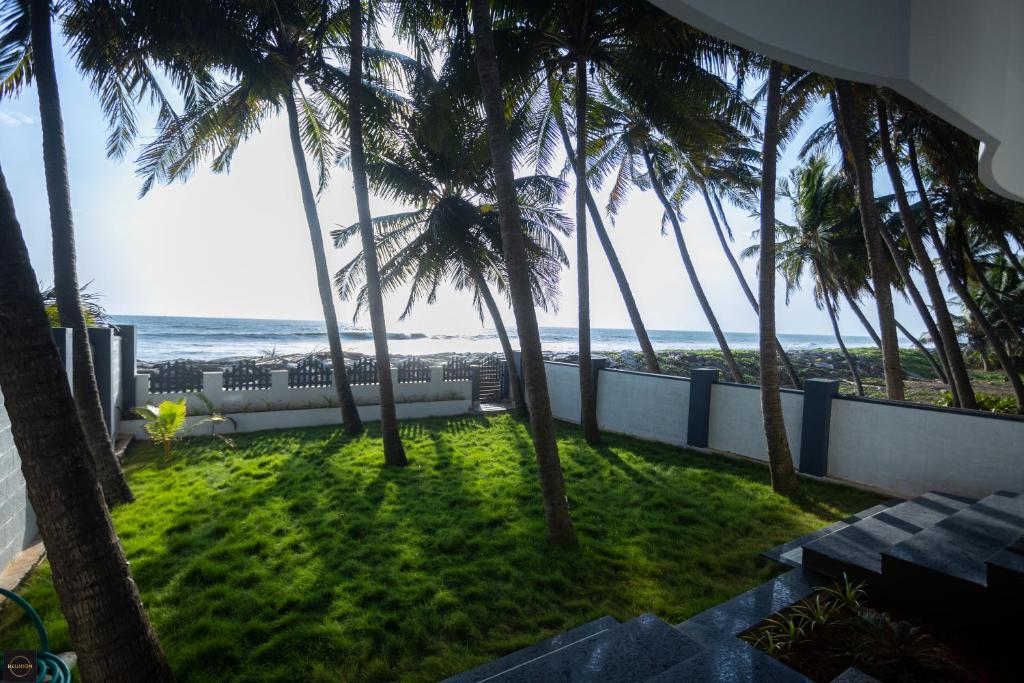 乌杜皮Reunion Ocean Manor - Beach House的阳台享有海景,种植了棕榈树。