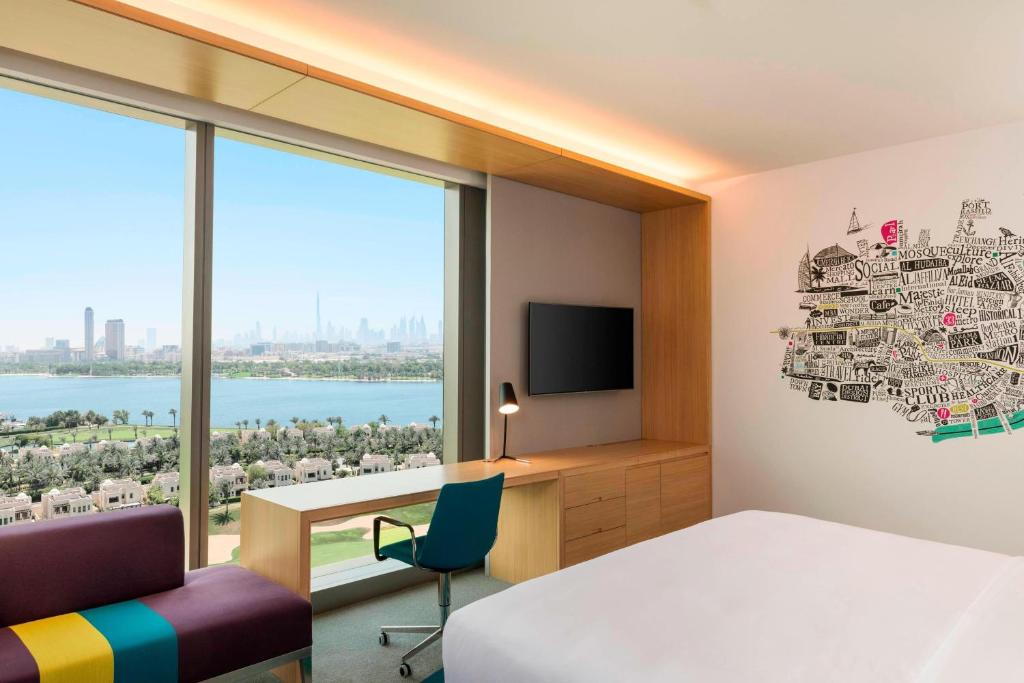迪拜Aloft Dubai Creek的一间卧室配有一张床、一张书桌和一台电视。