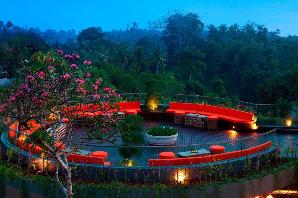 乌布巴厘岛乌布斯塔拉翠贡精选酒店的一个带红色沙发、桌子和鲜花的庭院