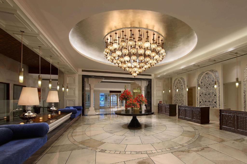 阿格拉ITC Mughal, A Luxury Collection Resort & Spa, Agra的大堂设有大吊灯和蓝色沙发