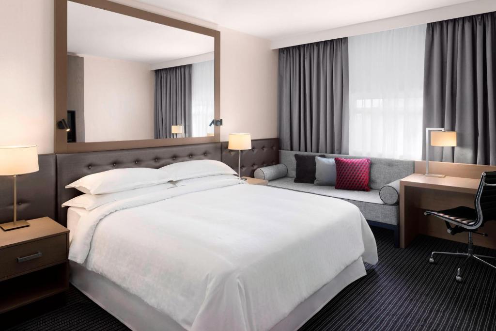 希灵登喜来登希斯罗酒店的酒店客房设有一张白色大床和椅子