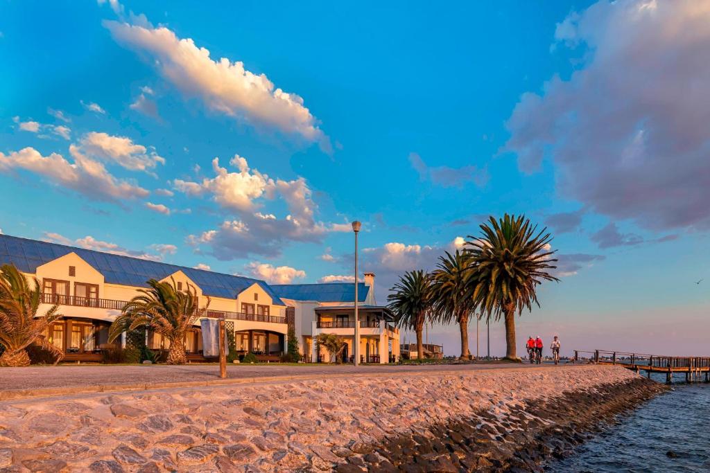 鲸湾港鹈鹕湾普罗提酒店 的一座位于海滩上的建筑,旁边是棕榈树