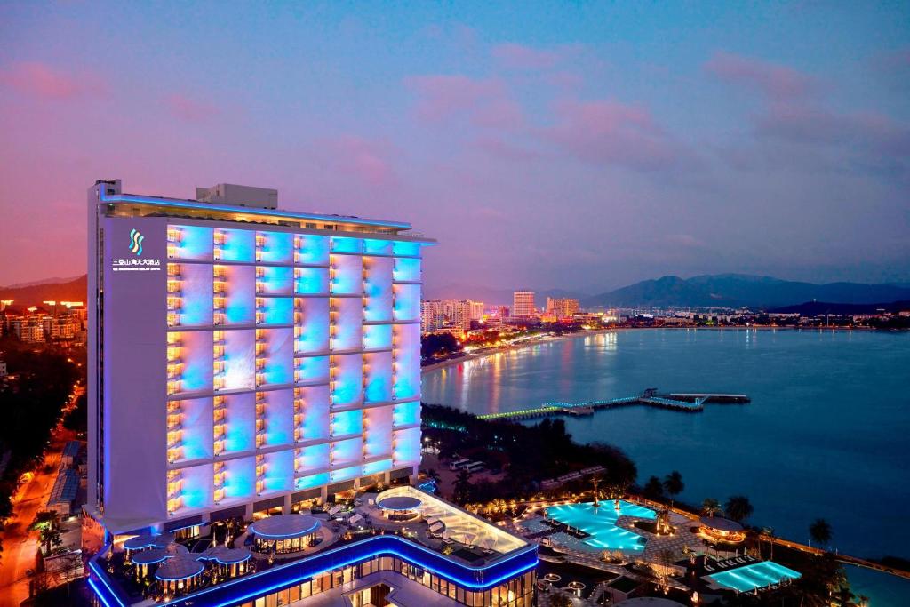 三亚三亚山海天大酒店，傲途格精选（万豪国际旗下酒店）的水体旁的一座有照明的建筑