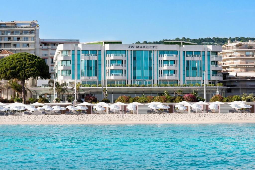 戛纳万豪加纳度假酒店的一个带遮阳伞和椅子的海滩和一家酒店
