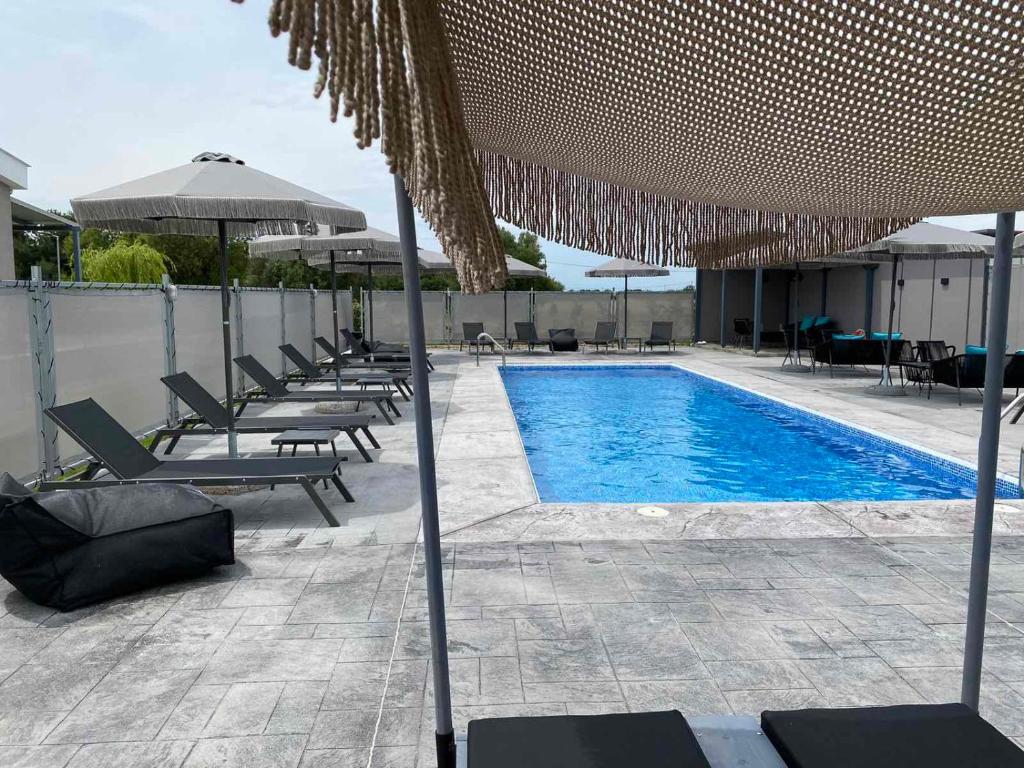 ÓrmosGERANI apartments的游泳池旁设有椅子和遮阳伞