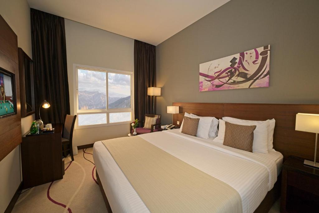 拉斯阿尔卡麦Action Hotel Ras Al Khaimah的一间设有大床和窗户的酒店客房