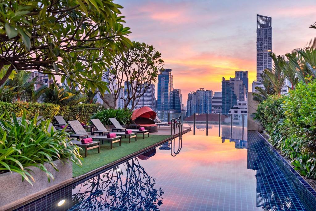 曼谷Aloft Bangkok - Sukhumvit 11的一个带躺椅的无边泳池和城市天际线