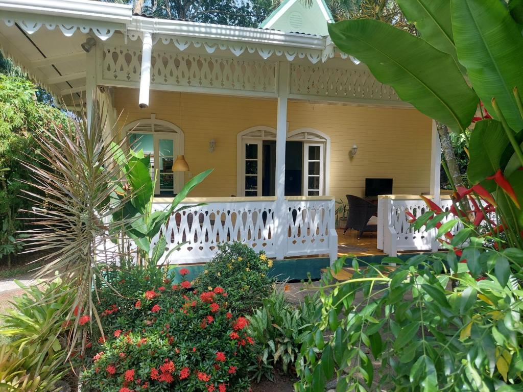 卡维塔Playa Negra Guesthouse的黄色房子,有白色门廊和鲜花