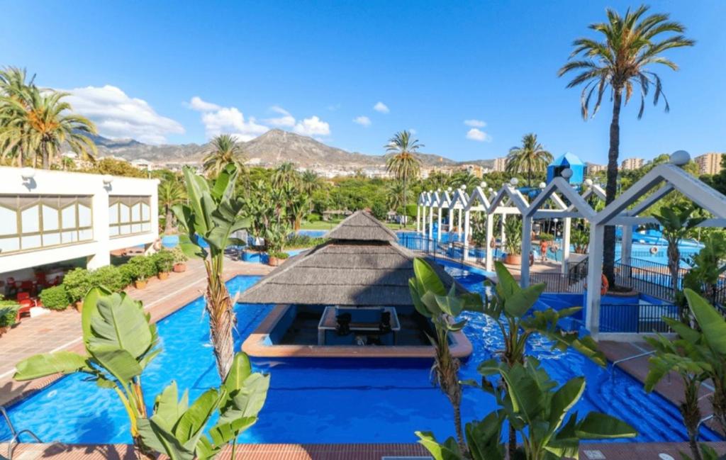 贝纳尔马德纳Benalbeach Smart Suite的棕榈树度假村的游泳池以及大楼