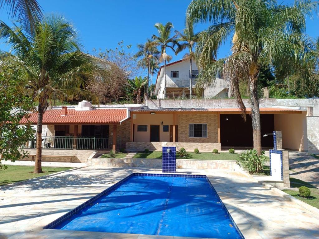 阿瓜斯迪林多亚Chácara Rancho Fundo的棕榈树屋前的游泳池