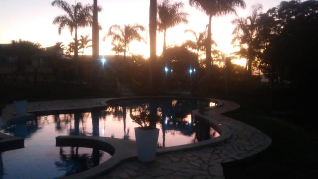 蒂拉登特斯Pousada Serra Azul的棕榈树和日落的游泳池