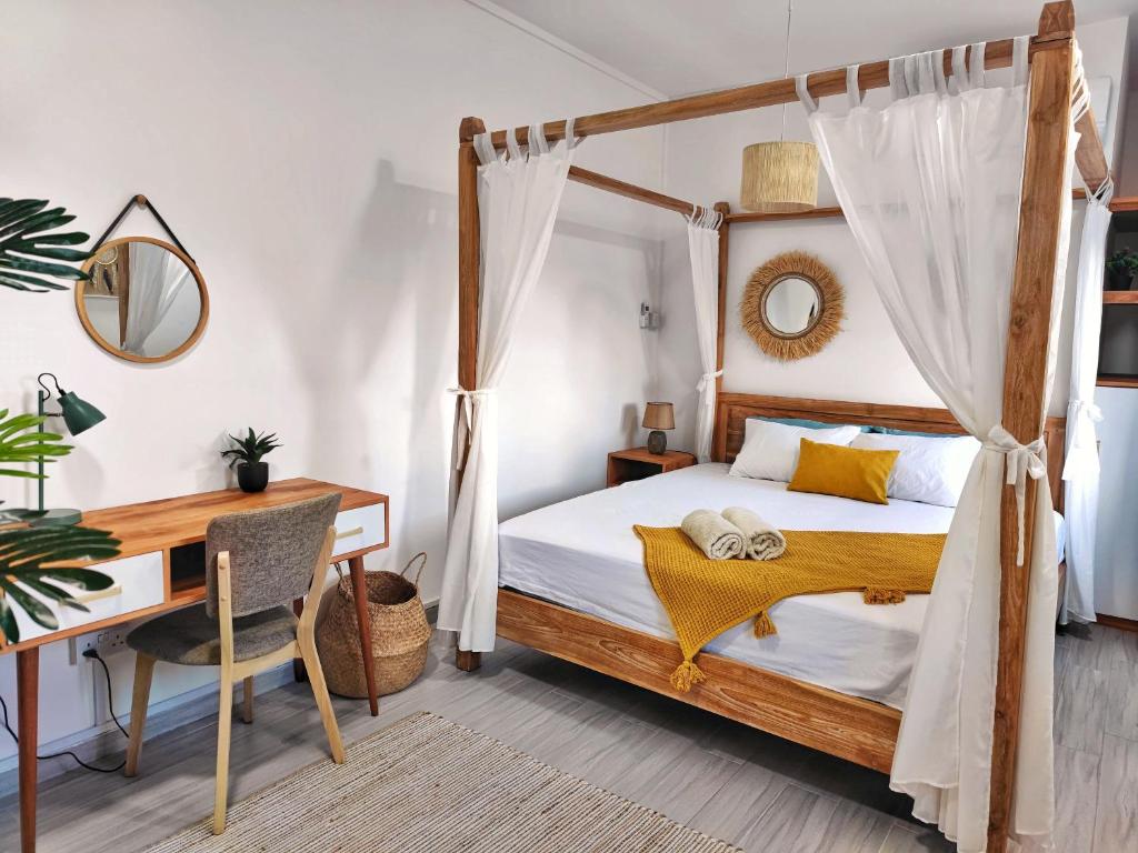 格兰贝伊Villa le Dodo - GBH的一间卧室配有一张天蓬床、一张桌子和一张书桌。