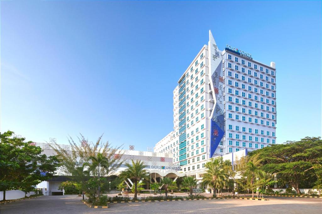马卡萨望加锡福朋喜来登酒店的一座高大的建筑,前面有棕榈树