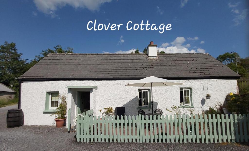 斯莱戈Clover Cottage的白色的房子,配有白色的围栏和雨伞