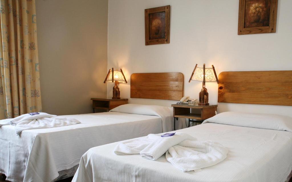 萨尔塔广场酒店的两张位于酒店客房的床,配有毛巾