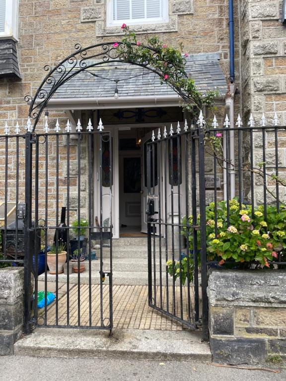 彭赞斯The Old Club的一座带鲜花的铁门的房屋的入口