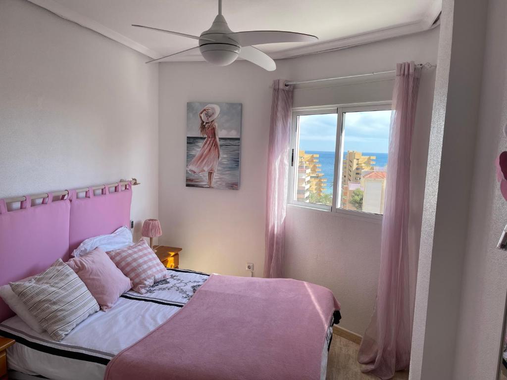 阿勒纳勒斯德尔索尔Sea-view 3-bedroom apartment near Alicante的卧室配有粉红色的床和窗户。