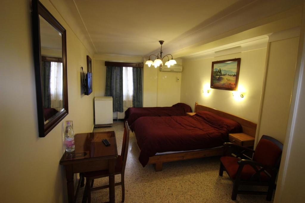 阿尔及尔Hotel Hydra的一间卧室配有一张床、一张桌子、一张床和一张桌子