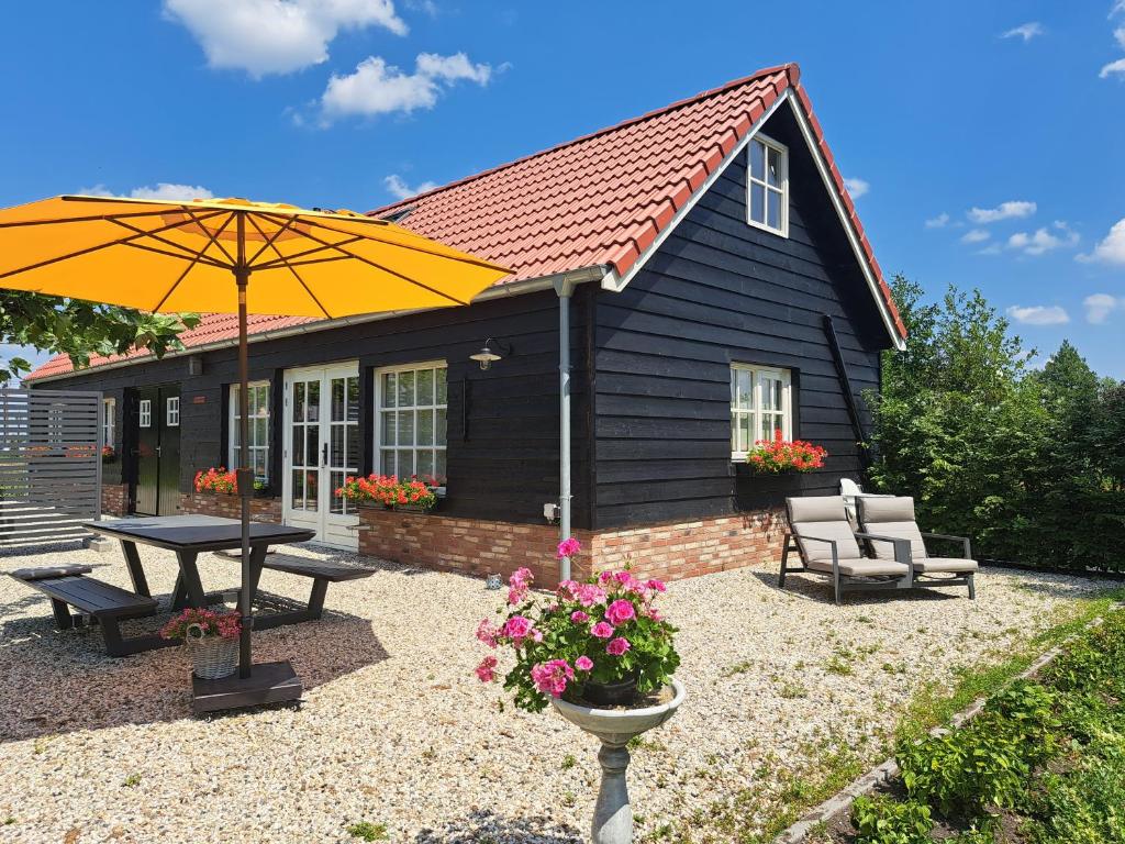 BergambachtB&B De Oase的一个带野餐桌和雨伞的小房子