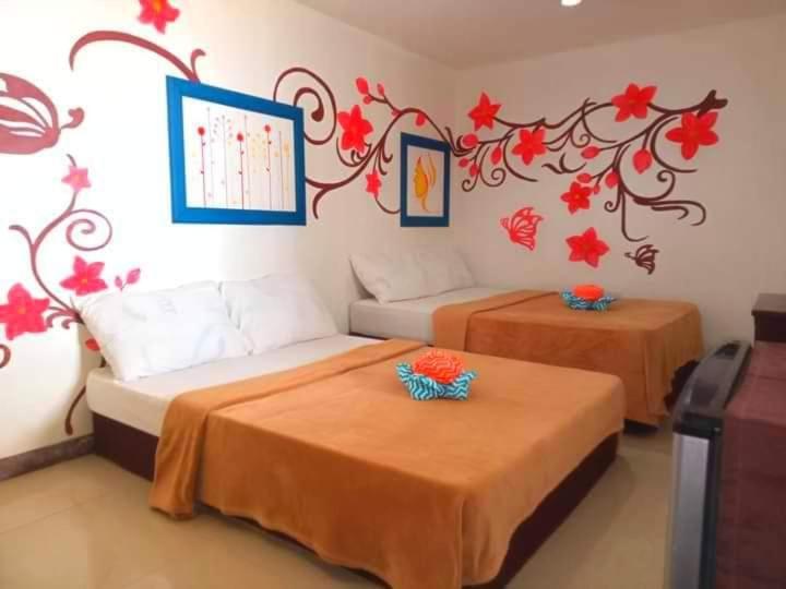 LookOslob Hotel Sébastian的墙上有红色鲜花的房间里,有两张床