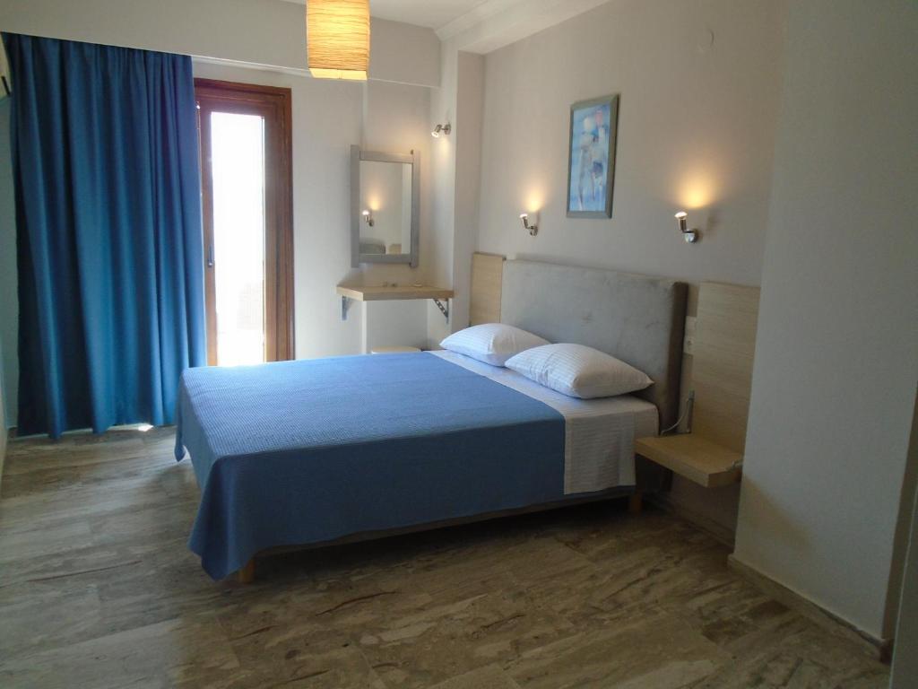 毕达哥利翁帕丽文尼酒店的一间卧室配有一张带蓝色床单的床和一扇窗户。