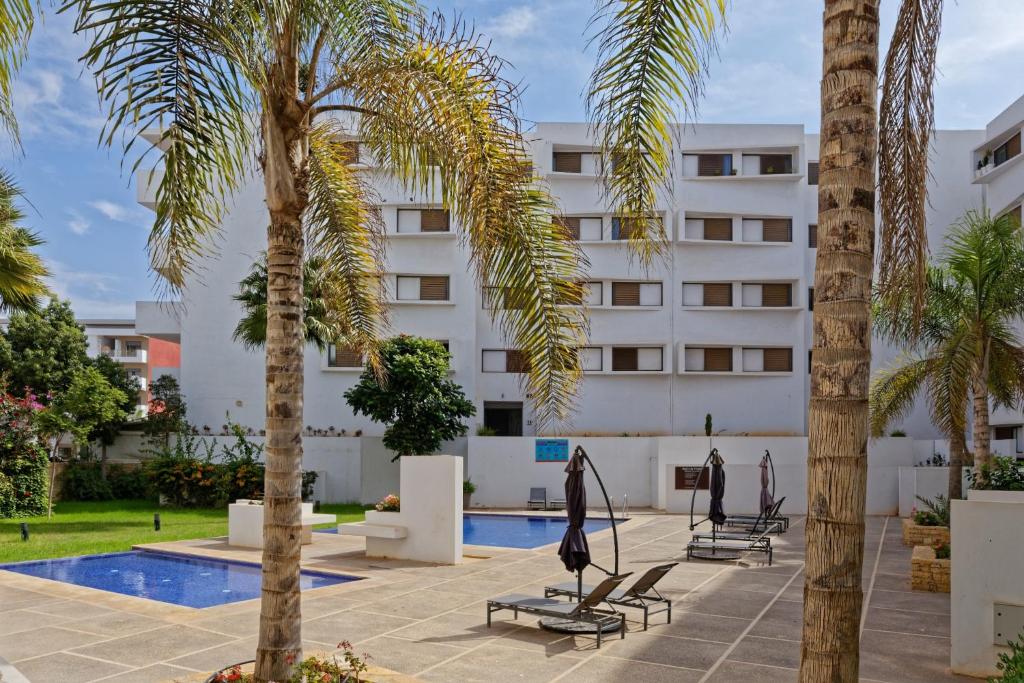 阿加迪尔Luxury Apartment 90sqm with Pool near Beach WIFI Unlimited Optical Fiber的棕榈树酒店和游泳池