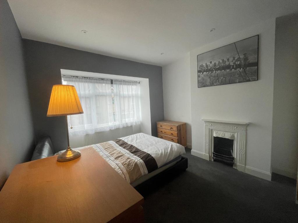 伦敦Entire house floor perfect for a couple - available for single too的一间卧室配有一张床、一盏灯和一个壁炉
