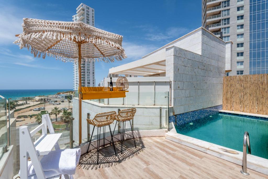 内坦亚Boutique Villa with Rooftop Pool的阳台设有游泳池、遮阳伞和椅子。