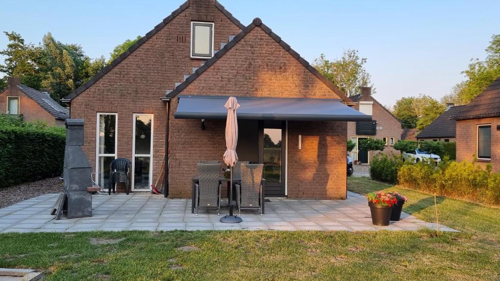 EwijkVakantiewoning Maas en Waal 195的一座房子,设有一座带遮阳篷和粉红色遮阳伞的庭院