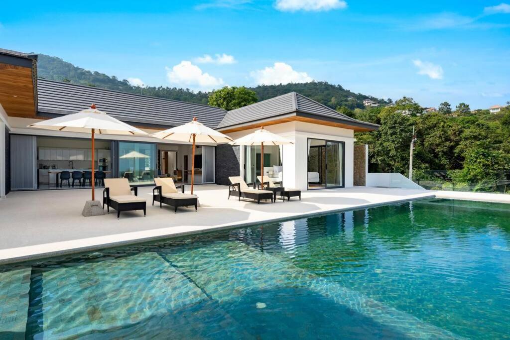 苏梅岛Villa Mandra - Beautiful 4 Bedroom Luxury Pool Villa KBR2的房屋旁的游泳池配有椅子和遮阳伞