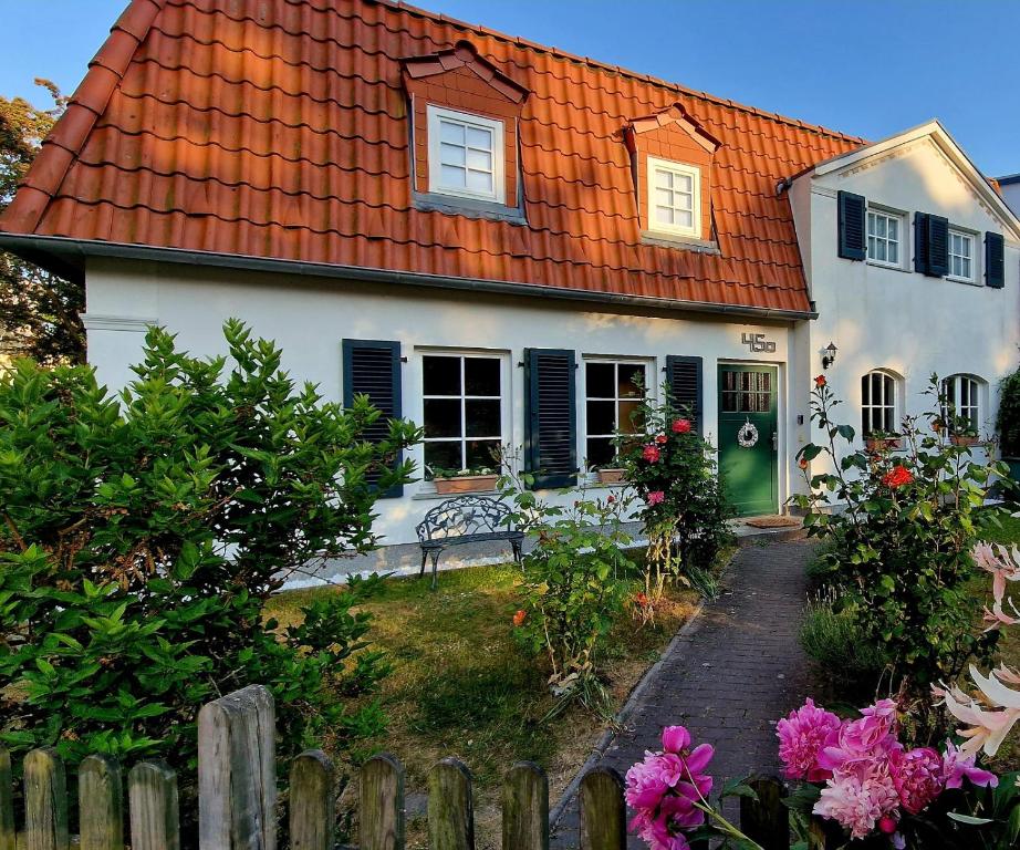 施特拉尔松德Haus mit 110qm und Garten 150m zum Wasser的白色的房子,有橙色的屋顶和栅栏
