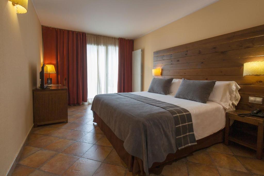 马萨纳Hotel Màgic Ski的一间卧室配有一张大床和木制床头板