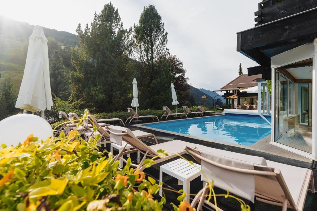 加舒恩普法伊费尔酒店的一个带椅子和遮阳伞的游泳池的度假酒店
