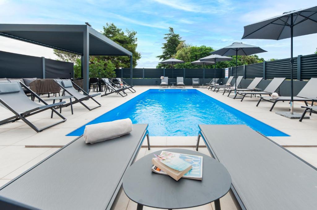 罗维尼Luxury Residence Levante的一个带躺椅和桌子的游泳池